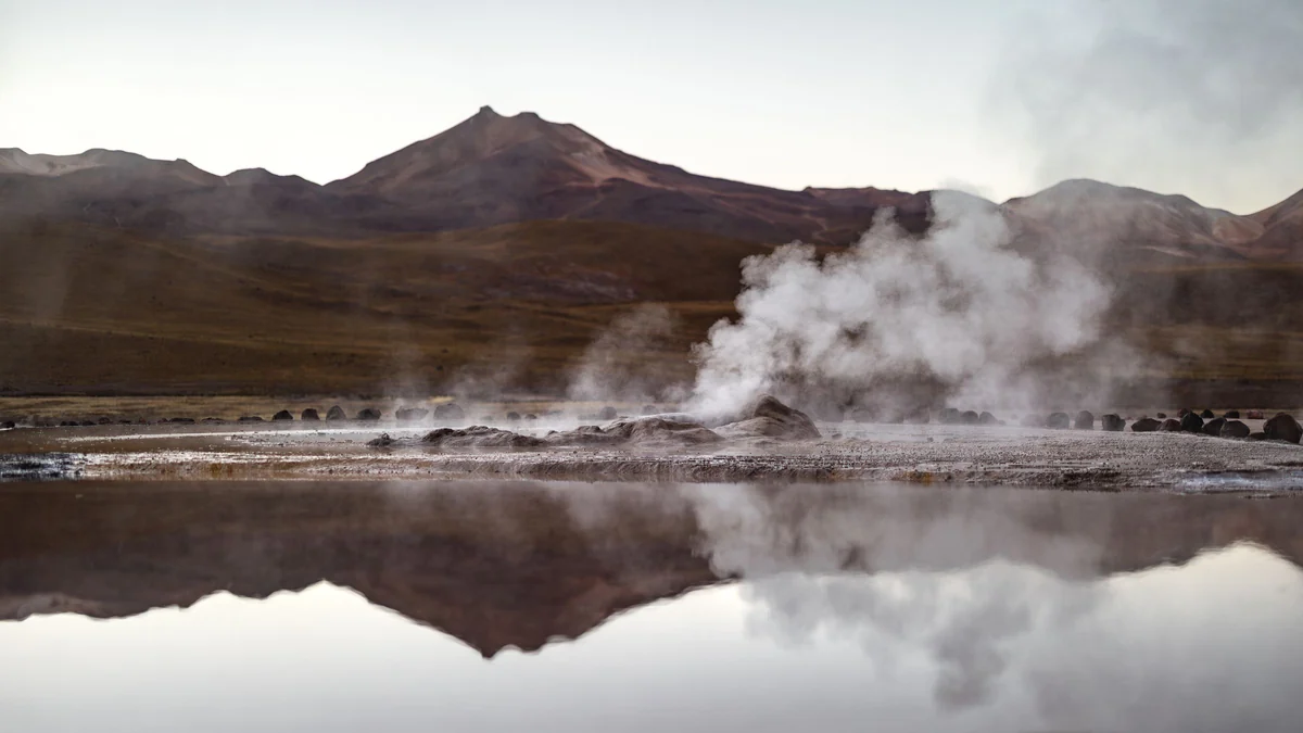 Vapor dos Geysers del Tatio refletido na água ao amanhecer