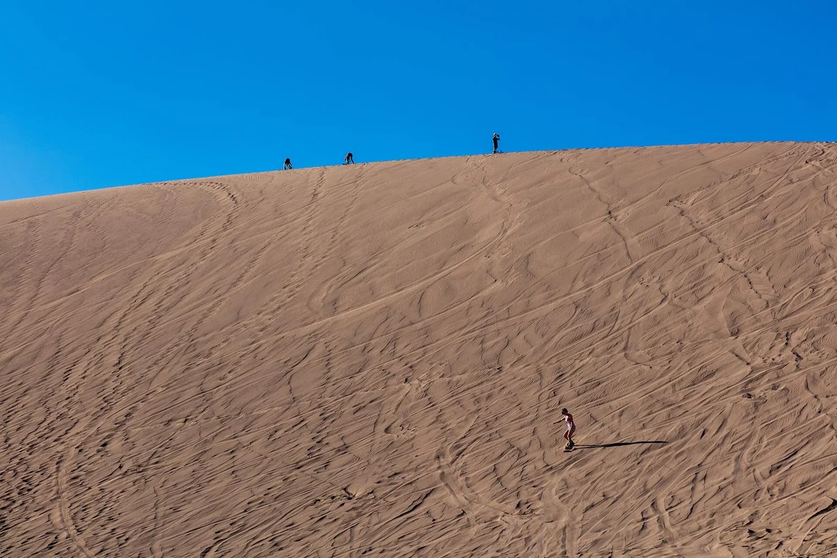 Pessoas no alto de uma duna do Valle de la Muerte, prontas para descer