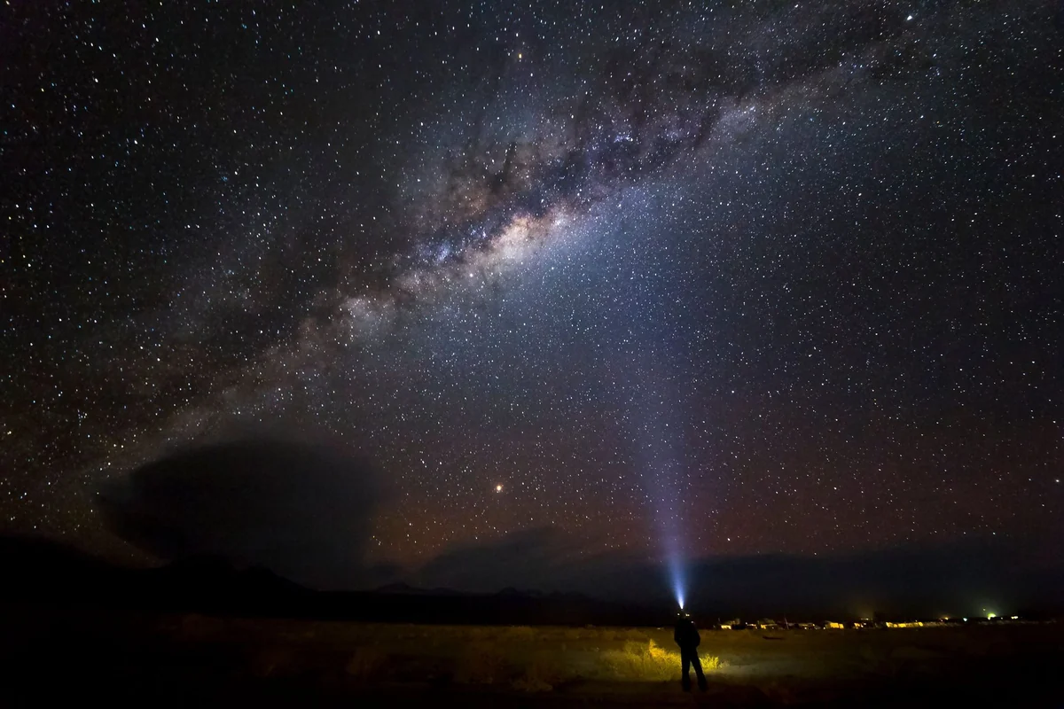 Pessoa com lanterna sob o céu estrelado do deserto